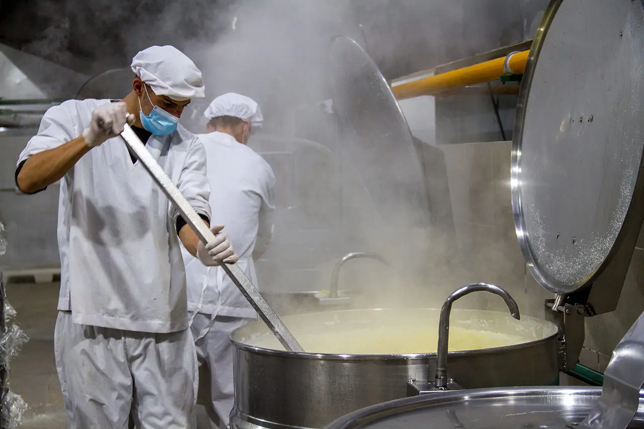 Cocineros de SASA revolviendo una preparación en una marmita industrial