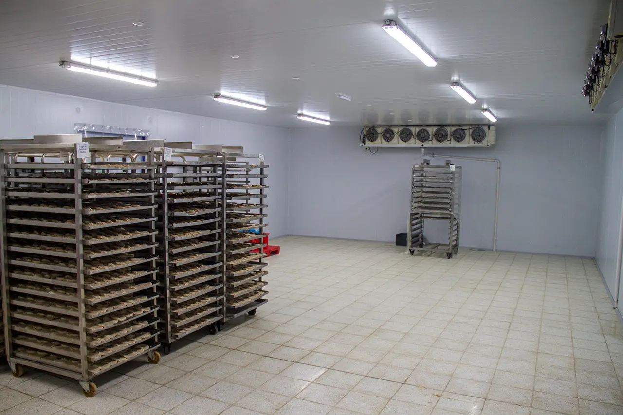 Cámara de frío con carros de bandejas de alimentos en la planta de SASA