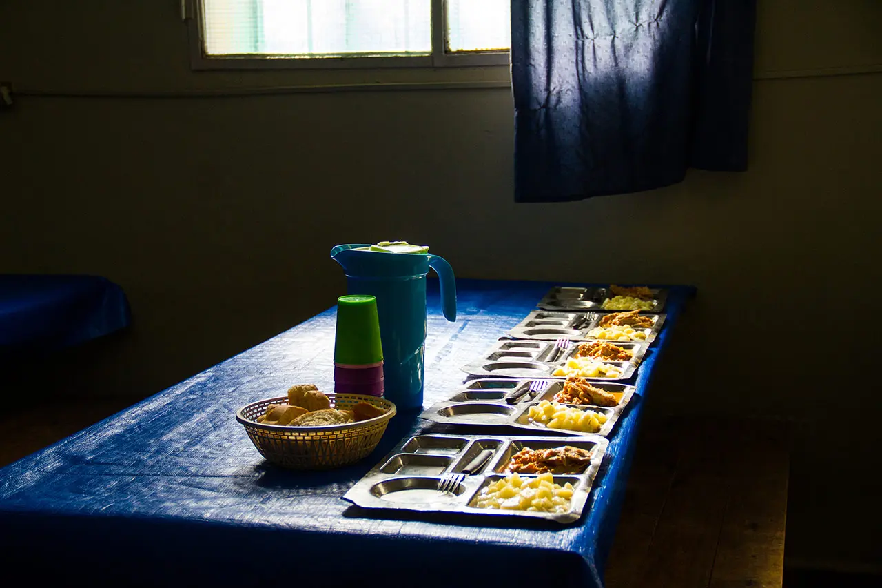 Mesa de comedor con bandejas de comida, pan y jarra listas para servir