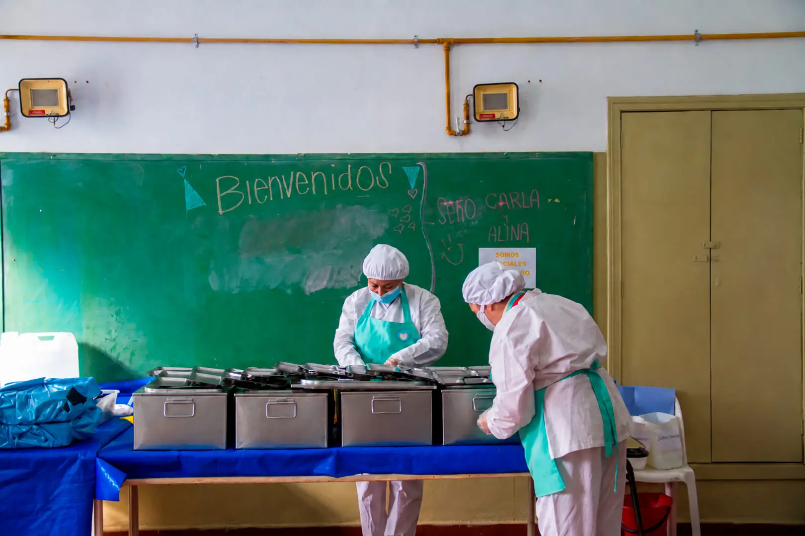 Personal de SASA preparando bandejas de comida en un comedor escolar