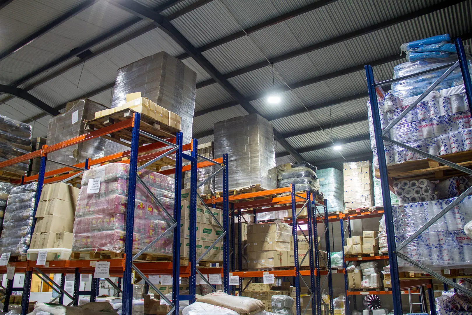 Depósito de alimentos con estanterías y mercadería paletizada para distribución